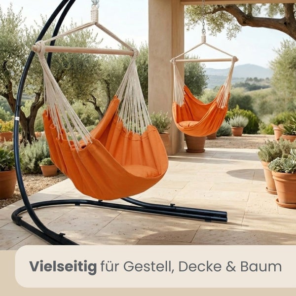 Oranger Hängesessel mit Holzstab an schwarzem Metallgestell auf einer Terrasse mit Pflanzen.