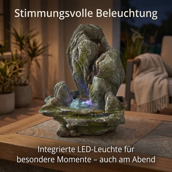 Steinoptik Gartenbrunnen mit integrierter LED Beleuchtung auf einem Steintisch im Außenbereich für eine stimmungsvolle Atmosphäre.