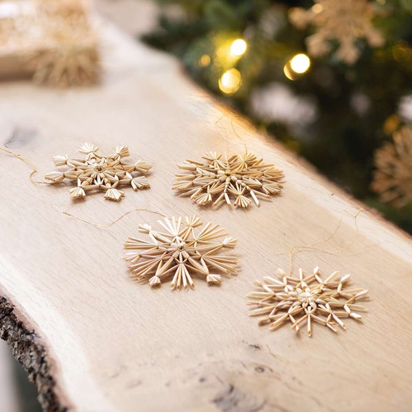 Vier Strohsterne als Weihnachtsdekoration auf einem Holztisch