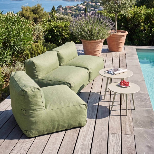 Grüne Gartenlounge-Elemente auf einer Holzterrasse am Pool mit Beistelltischen und Terrakotta-Pflanzkübeln.