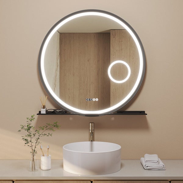 Runder Badezimmerspiegel mit LED Beleuchtung, integrierter Uhr und Ablage über einem runden Waschbecken mit Armatur.