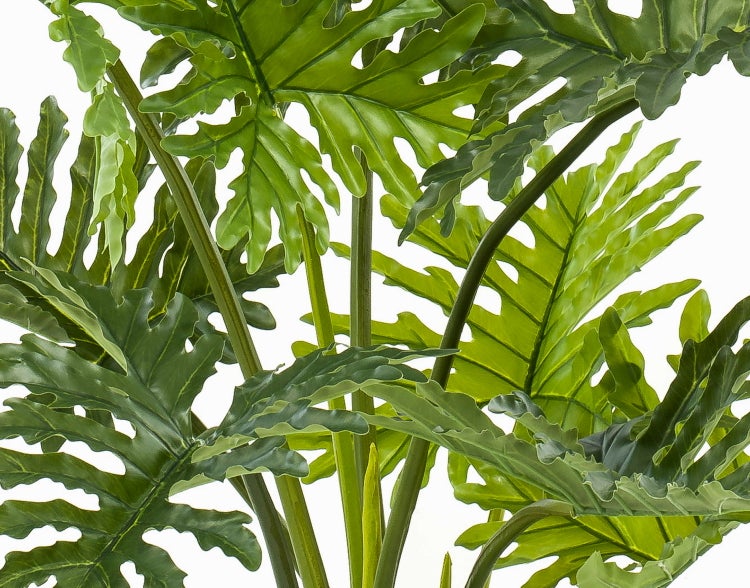 Künstliche Pflanze mit grünen Blättern und Stielen in einem schwarzen Kunststofftopf.