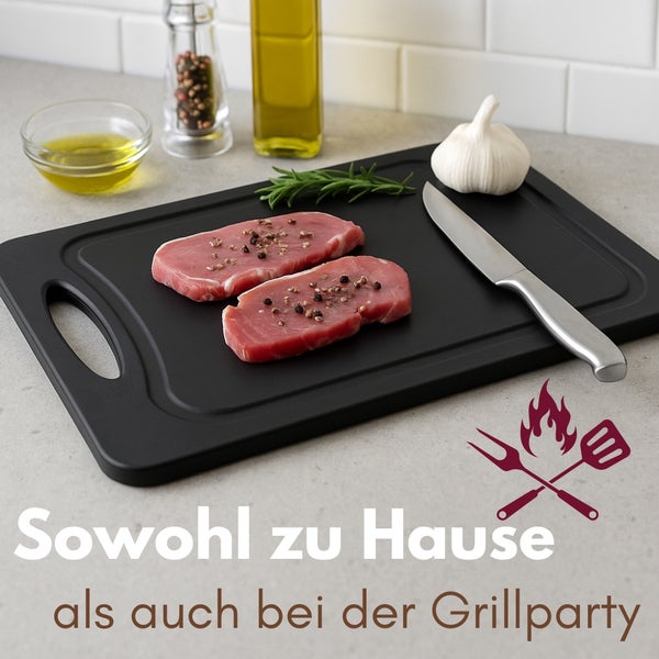 Schwarzes Schneidebrett mit Fleisch, Messer und Knoblauch