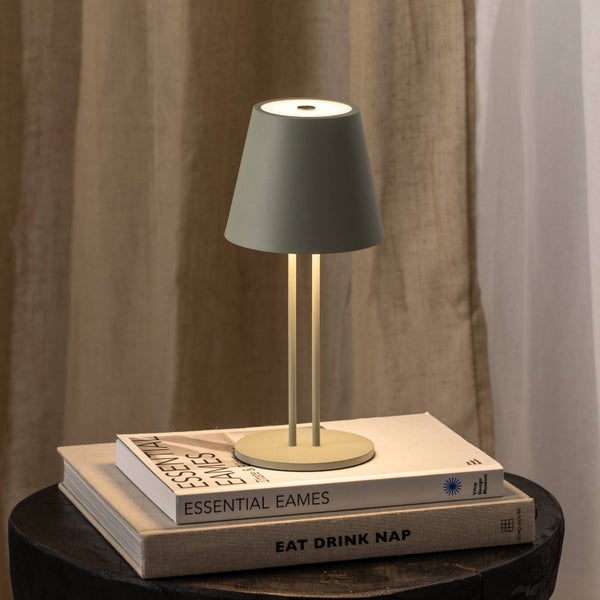 Moderne kabellose LED-Tischleuchte mit konischem Schirm und zwei schlanken Stäben, auf Büchern platziert in einer hellen, organisierten Umgebung.