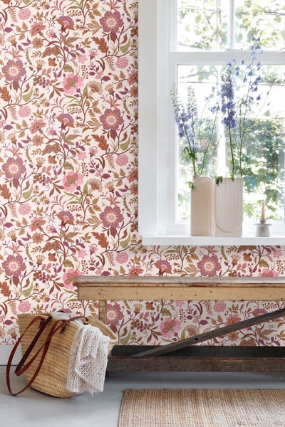 Helle Flurgestaltung mit einer Tapete im floralen Muster in Rosa und Braun neben einer weißen Tür.