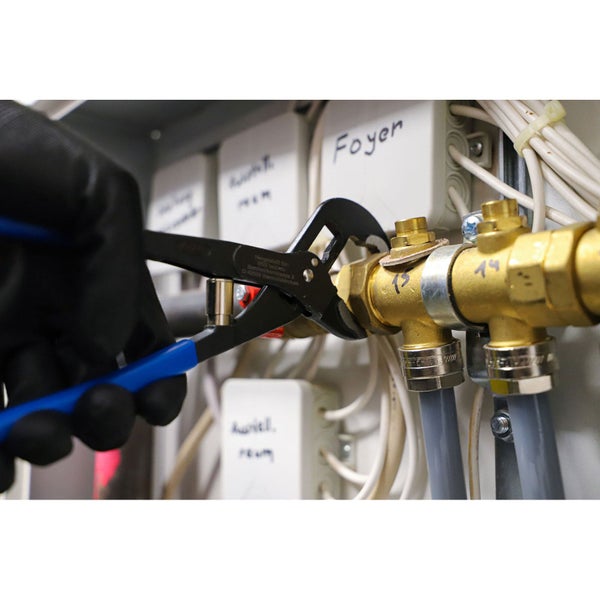 Ein Installateur montiert mit einer Rohrzange eine Sanitärinstallation.