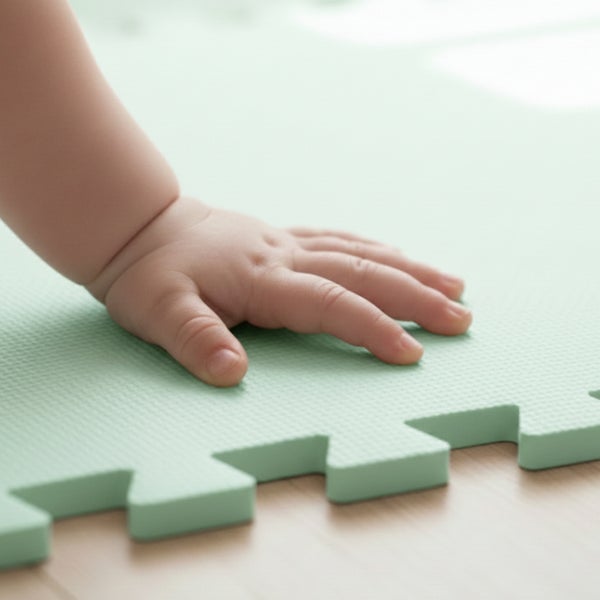 Kinderhand auf einer strukturierten Schaumstoff-Puzzlematte mit verzahnten Kanten auf einem Holzboden.