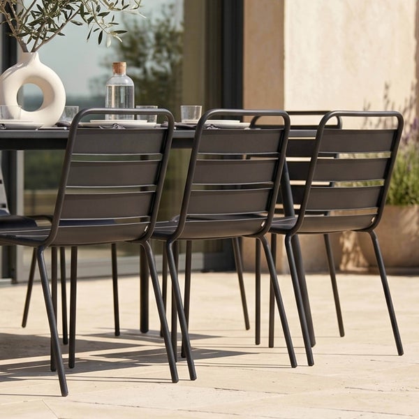Moderne Gartenstühle aus Metall mit horizontalen Lamellen an einem passenden Tisch auf einer hellen Terrasse.