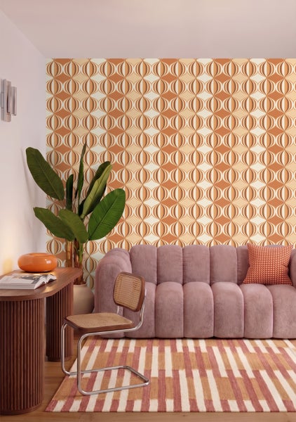 Wohnzimmer mit retro geometrischer Tapete, geripptem Sofa, Holzschreibtisch in Lamellenoptik, Stuhl mit Wiener Geflecht und gemustertem Teppich.