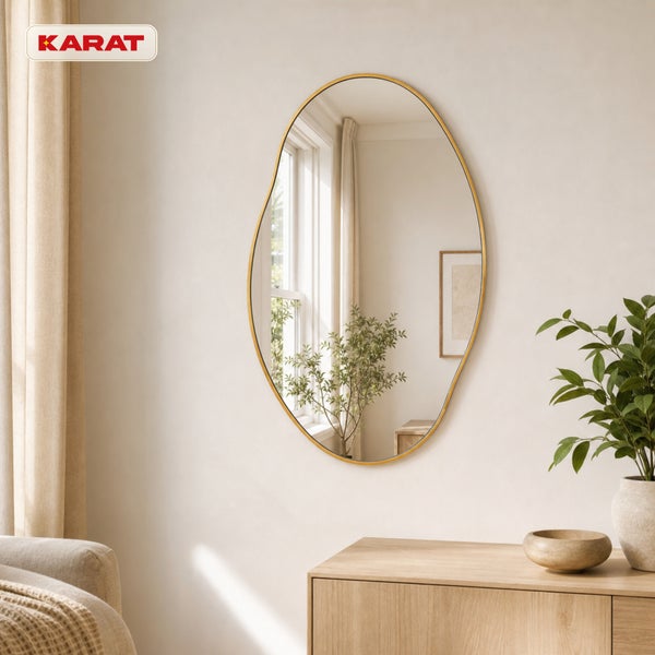 Wandspiegel mit unregelmäßiger organischer Form und Rahmen an einer hellen Wand über einem Sideboard aus Holz, Karat Logo.