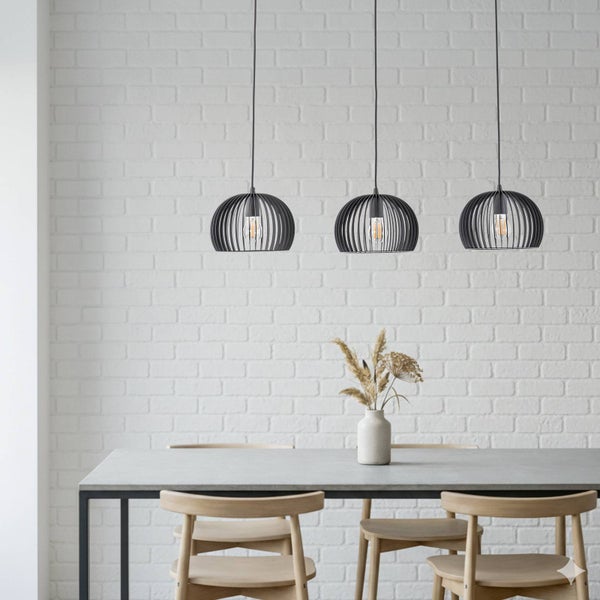 Drei schwarze Pendelleuchten aus Metall über einem Esstisch mit Stühlen.