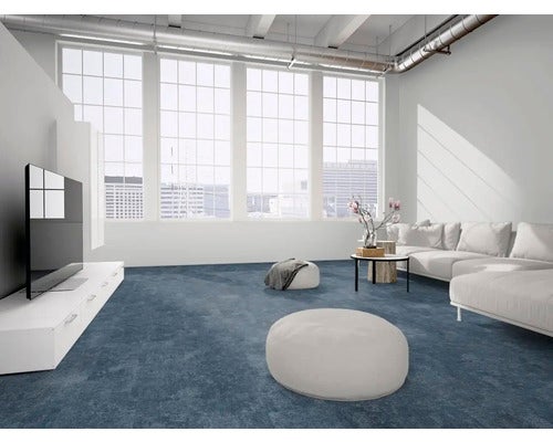 Moderner Wohnbereich im Industrie-Stil mit großen Fenstern, weißem Sofa, Fernsehmöbel und einem dunkelblauen Teppichboden in Steinoptik.