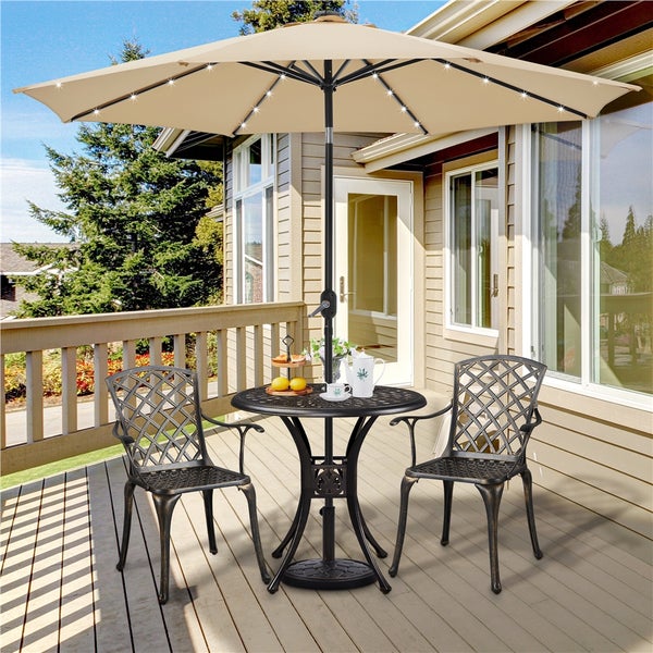 Gartenmöbel-Set mit rundem Metalltisch, zwei Stühlen und beigem Sonnenschirm mit integrierter LED-Beleuchtung auf einer hellen Holzterrasse.