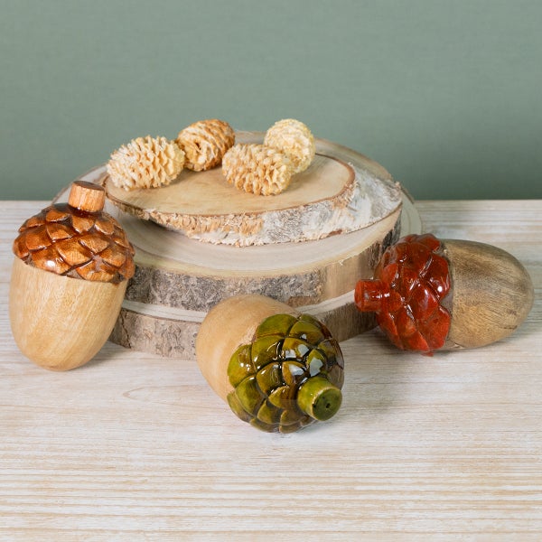 Dekorative Eicheln aus Holz und Zirbeln auf Holzscheiben