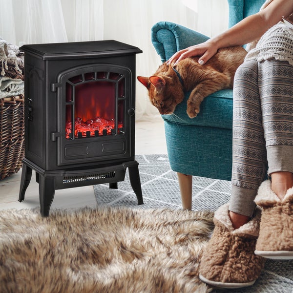Dekorativer Elektrokamin mit simulierten Flammen neben einem Sessel, auf dem eine Katze liegt