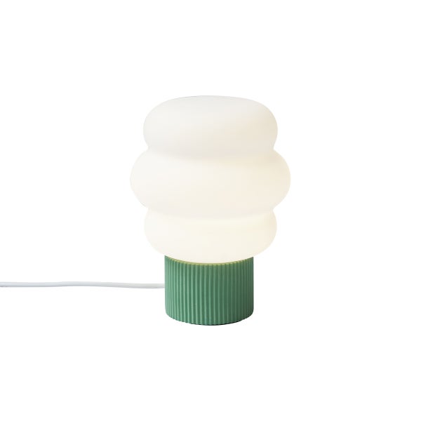 Tischleuchte mit grünem geriffeltem Sockel und weißem, wellenförmigem Glasschirm.