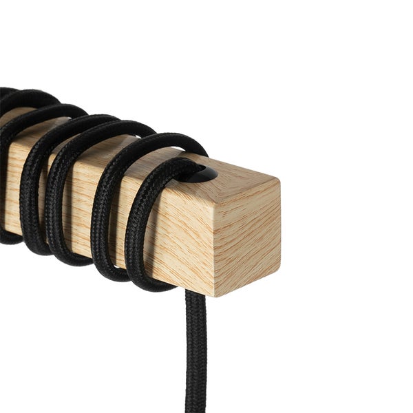 Detail einer Lampe mit Holzelement und schwarzem Textilkabel
