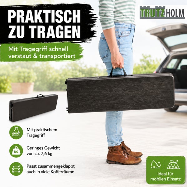 Person trägt einen zusammengeklappten Trutzholm Klapptisch mit Tragegriff, ideal für mobilen Einsatz, geringes Gewicht von etwa 7,6 Kilogramm.