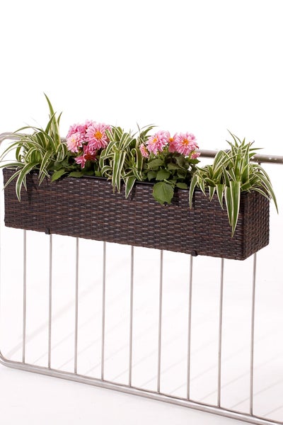 Rechteckiger Balkonkasten in Flechtoptik mit rosa Blumen und Grünpflanzen an einem Metallgeländer.