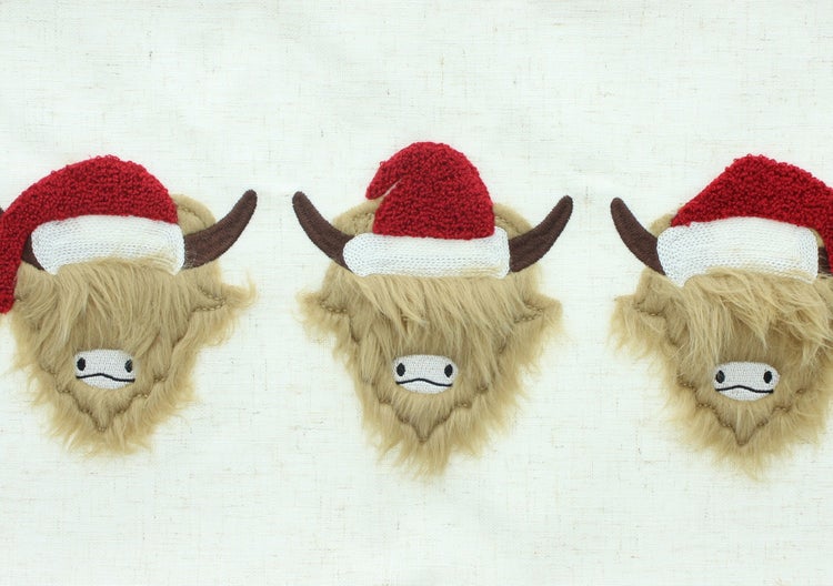 Drei dekorative Hochlandrinder mit Weihnachtsmützen