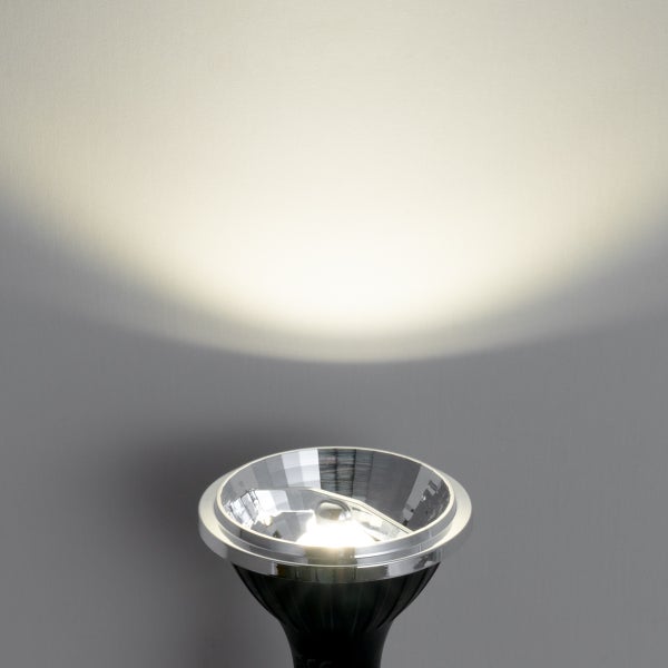 Eingeschalteter LED-Reflektorstrahler mit warmweißem Lichtstrahl an einer Wand.