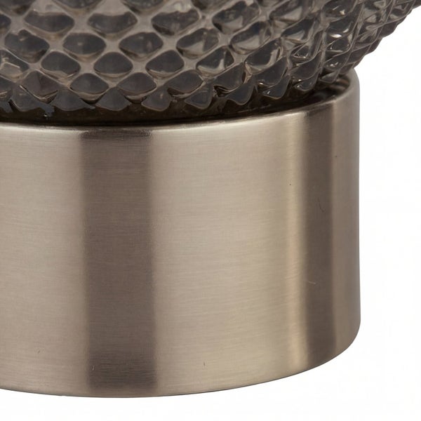 Detailaufnahme einer Tischleuchte mit gemusterter Glasoberfläche und Metallsockel