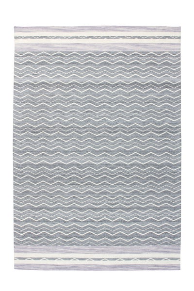Ein moderner, gemusterter Teppich mit Zickzack-Design liegt in einem hellen, stilvoll eingerichteten Schlafzimmer mit Pflanzenakzenten.