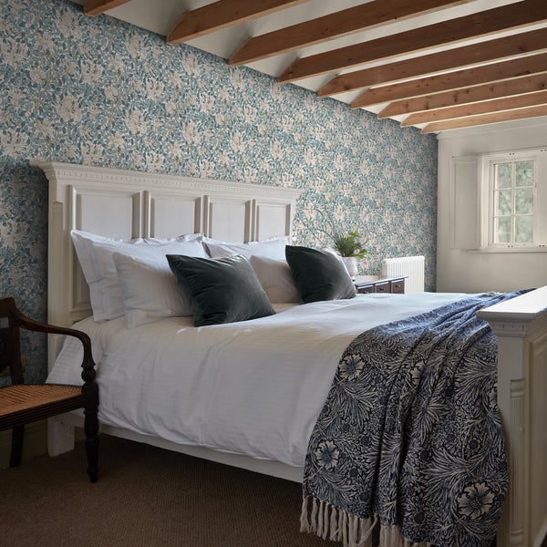 Schlafzimmer mit gemusterter Tapete, Bett und Holzdecke