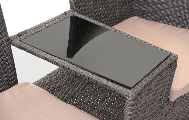 Beistelltisch mit Glasplatte zwischen zwei Polyrattan-Gartensesseln inklusive Sitzkissen.