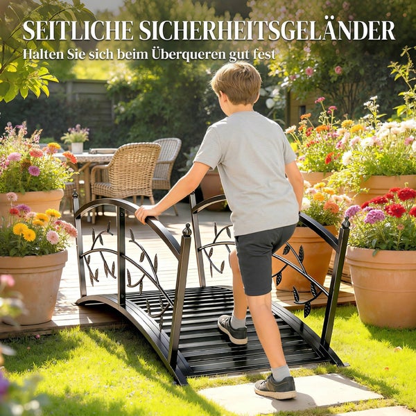 Kleine Gartenbrücke aus Metall mit Sicherheitsgeländern in einem blühenden Garten mit Kind.