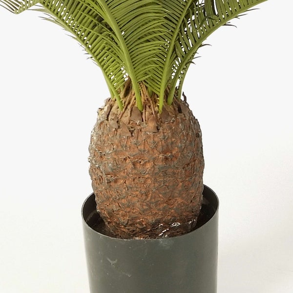 Nahaufnahme einer Kunstpflanze mit langen schmalen grünen Blättern.