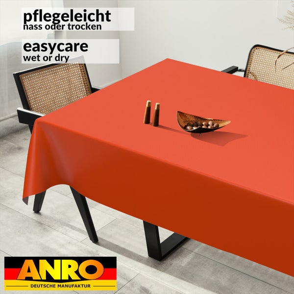 Rechteckige orangefarbene Tischdecke auf einem modernen Esstisch in einem hellen Raum, pflegeleicht, ANRO Deutsche Manufaktur Logo.
