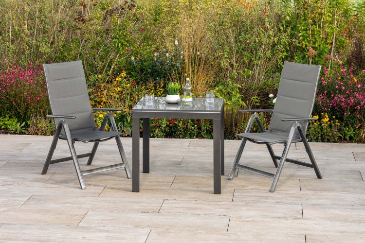 Gartenset mit Tisch aus Metall und Glas sowie zwei Klappstühlen auf einer Terrasse