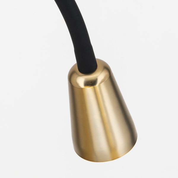 Detailaufnahme einer goldenen Lampenfassung mit schwarzem Kabel