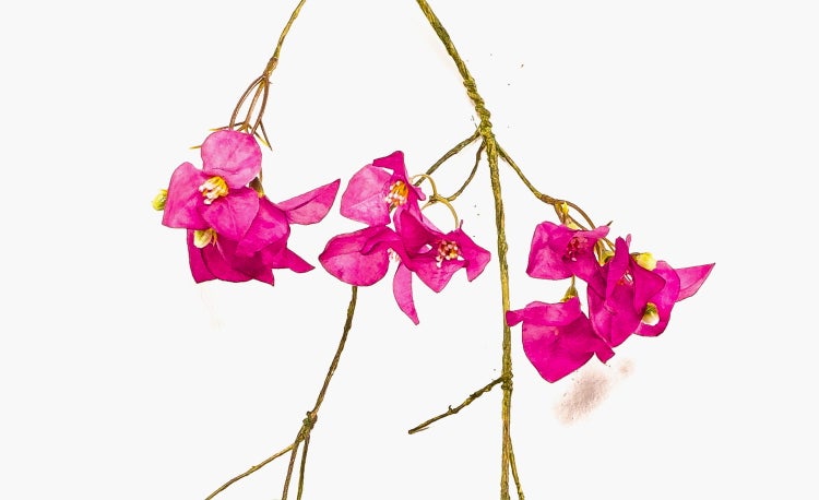 Künstliche Palme mit texturiertem Stamm und grünen Wedeln in einem schwarzen Topf.