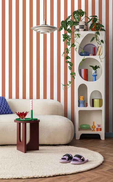 Wohnzimmer mit gestreifter Tapete, Sofa, Beistelltisch und Regal.