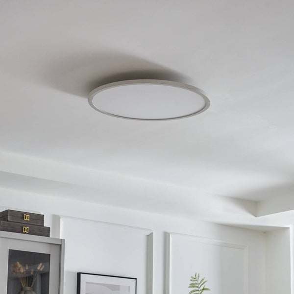 Runde LED-Deckenleuchte mit flachem silberfarbenem Rahmen an einer weißen Zimmerdecke in einem hellen Wohnraum.