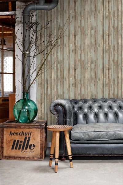 Interieuransicht mit Sofa, Hocker und Dekoration vor einer Wand mit Holzpaneel-Tapete