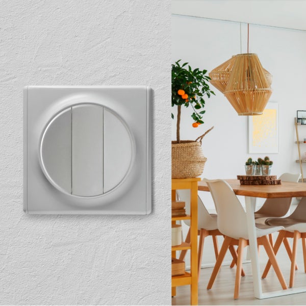 Ein moderner Lichtschalter mit rundem Einsatz auf einer strukturierten Wand neben einer Ansicht eines hellen Esszimmers.