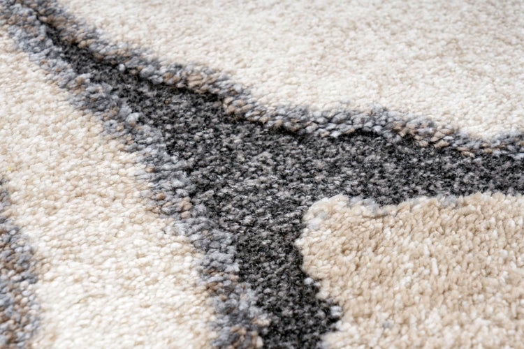 Detailansicht eines Teppichs mit strukturierter Oberfläche und geschwungenem Muster.
