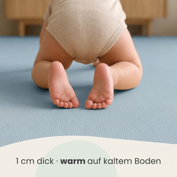Ein Kleinkind krabbelt auf einer ein Zentimeter dicken Spielmatte, die vor kalten Boden schützt.