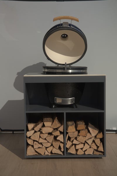 Keramikgrill auf Unterschrank mit Holzscheiten