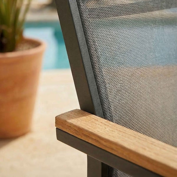 Nahaufnahme eines Gartenstuhls mit Metallgestell, Holzarmlehne und Textilgewebe.