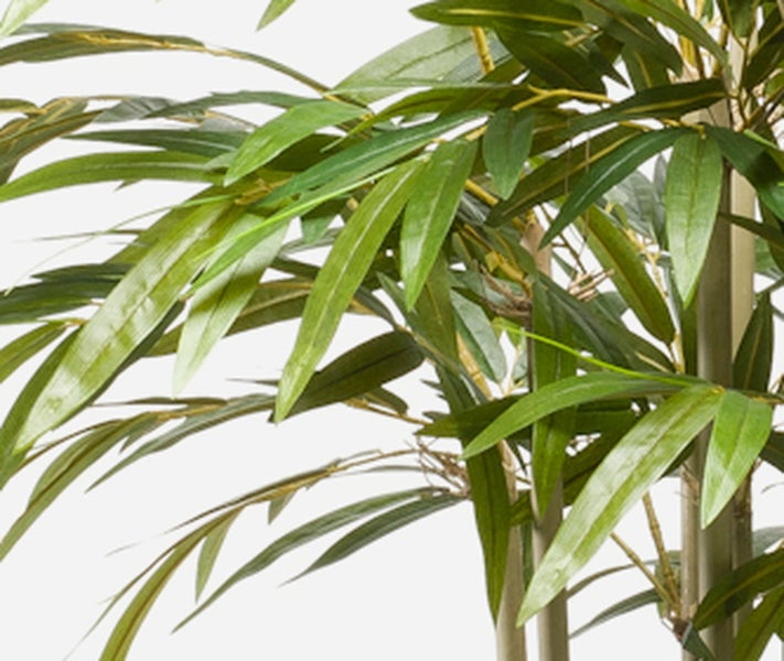 Detailaufnahme einer künstlichen Bambuspflanze mit naturgetreuen Halmen und grünen Blättern.