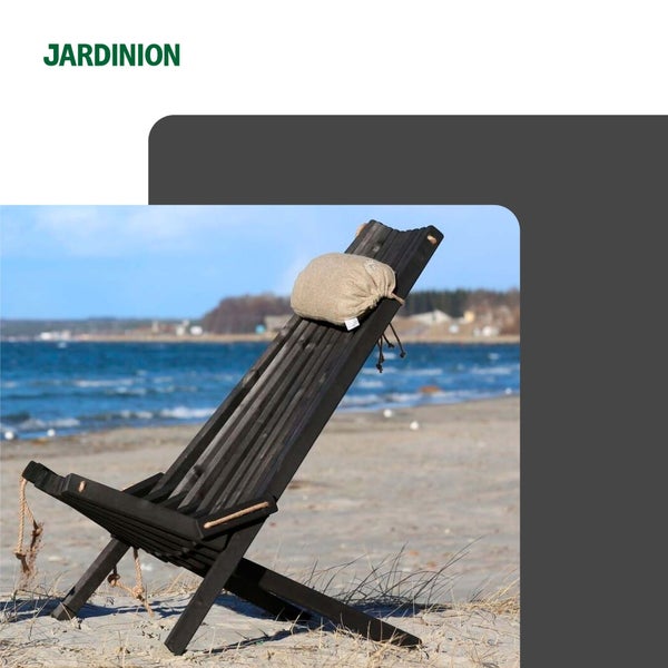 Jardinion Logo. Ein schwarzer Gartenstuhl aus Holz mit Nackenkissen steht an einem hellen Strand am Wasser.