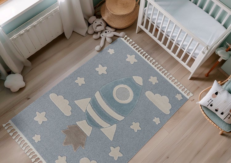 Kinderspielteppich mit Raketenmotiv in einem hell eingerichteten Kinderzimmer mit Kinderbett und Rattan Sessel.