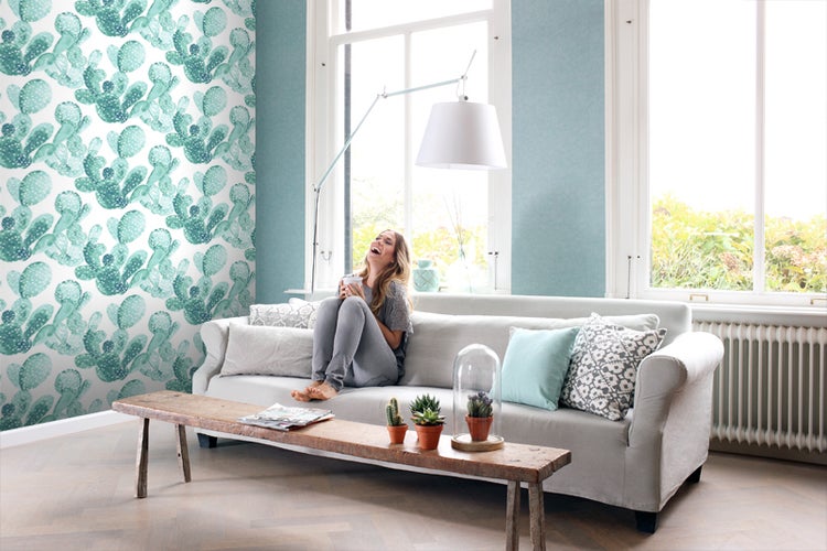 Wohnzimmer mit Kakteenmuster-Tapete, Sofa und Holztisch