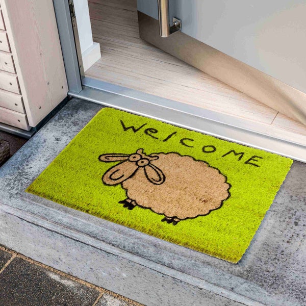 Fußmatte mit Willkommensaufschrift und Schafsmotiv vor einer Haustür