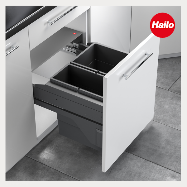 Ausziehbares Mülltrennsystem mit zwei grauen Behältern montiert in einem weißen Küchenunterschrank. Hailo Logo.