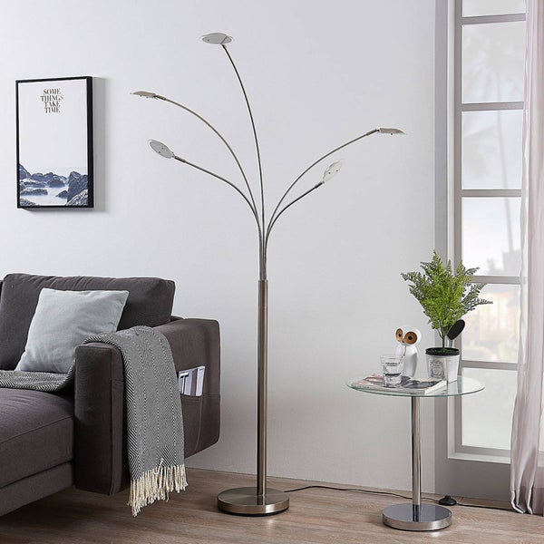 Moderne Stehleuchte mit fünf verstellbaren Armen in einem hellen Wohnzimmer neben einem grauen Sofa und einem Glastisch.